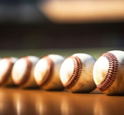 A row of used baseballs on a sunlit wooden surface