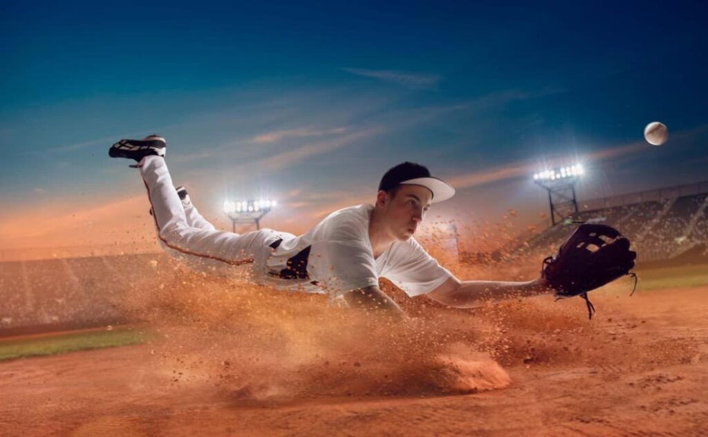 A player dives to catch a baseball, dirt flying in the air