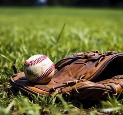 A worn baseball and glove on green grass