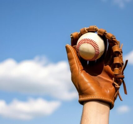 A gloved hand catching a baseball against a blue sky